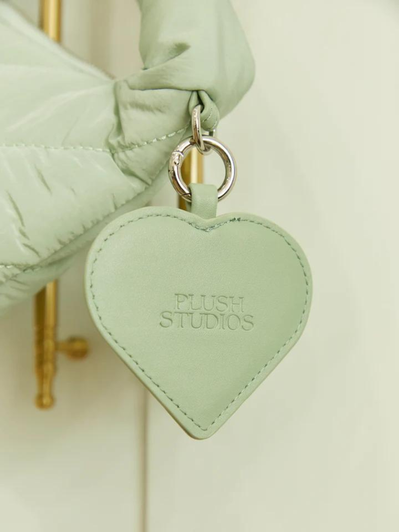 heart-shaped mirror on sage coloured cushion bag