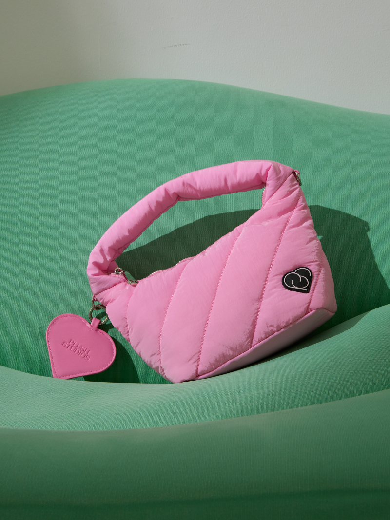 Pink Plush Love Lola Bag with heart-shape mirror on green sofa