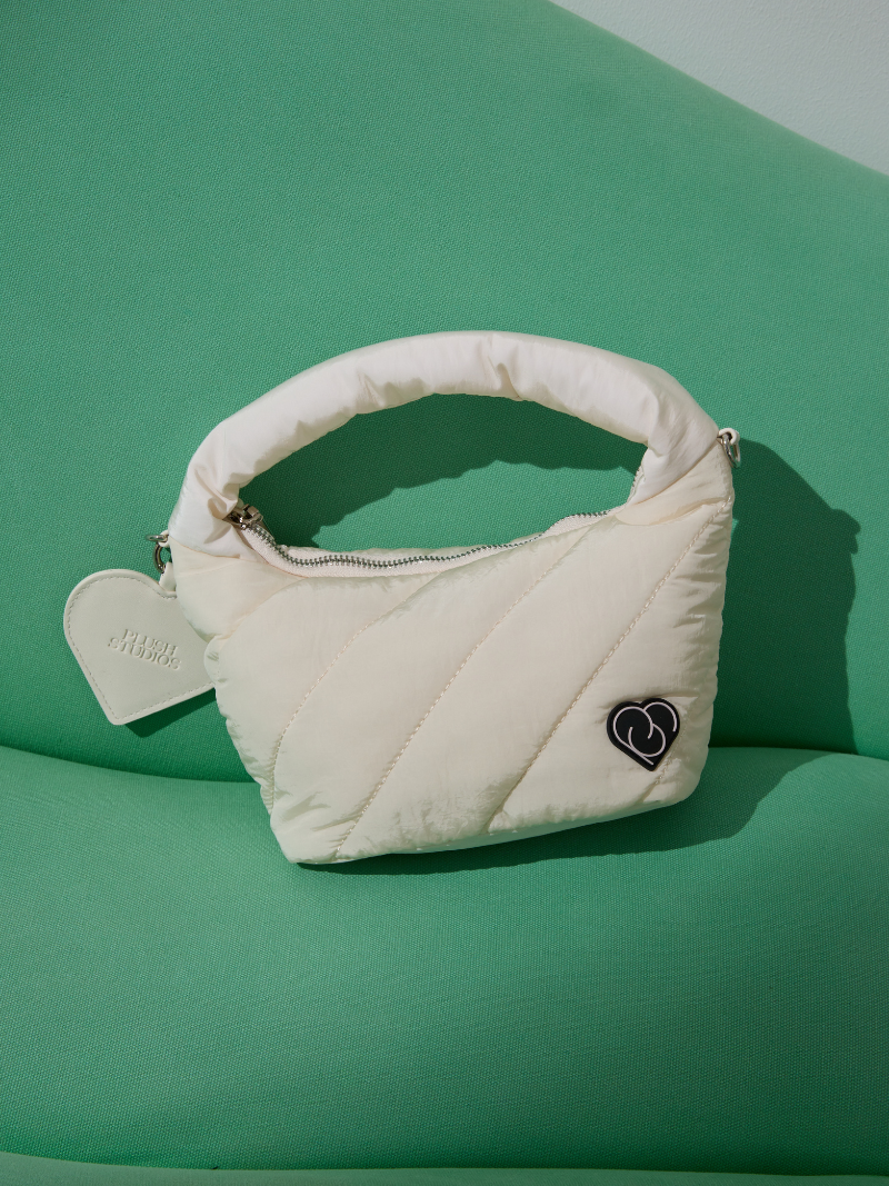 white coloured ladies handbag on green sofa